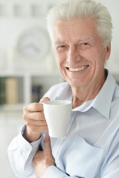 Porträt eines lächelnden älteren Mannes, der zu Hause Kaffee trinkt