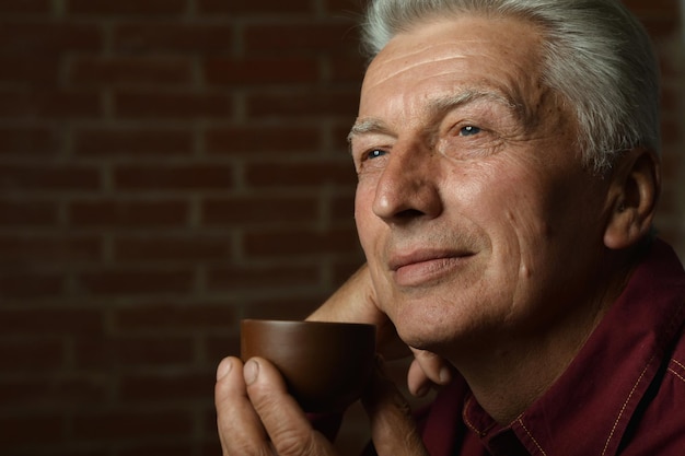 Porträt eines lächelnden älteren Mannes, der zu Hause Kaffee trinkt
