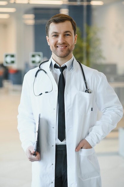 Porträt eines lächelnden Arztes in Uniform, der in der Halle der Medizinklinik steht