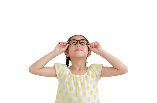 Porträt eines lächelnden asiatischen kleinen Mädchens, das eine Brille trägt und auf weißem Hintergrund nach oben schaut