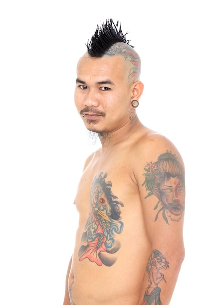 Porträt eines lächelnden asiatischen Punk-Typs mit Mohawk-Frisur, Piercing und Tätowierung auf weißem Hintergrund