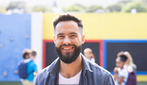 Foto porträt eines lächelnden, bärtigen kaukasischen grundschullehrers im freien, kopierraum