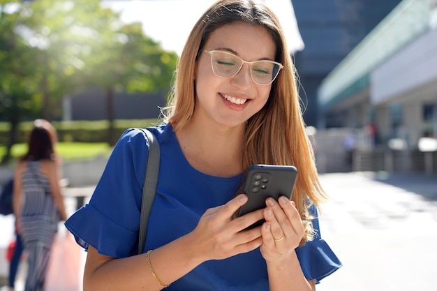 Porträt eines lächelnden Brasilianers, der im Sommer im Freien auf dem Smartphone tippt