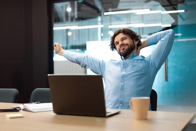 Porträt eines lächelnden Geschäftsmannes, der sich im Büro auf dem Stuhl entspannt