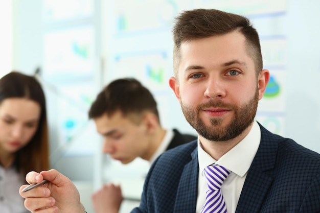 Foto porträt eines lächelnden geschäftsmannes mit kollegen bei einer besprechung im hintergrund im büro