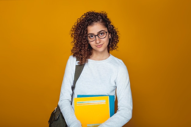 Porträt eines lächelnden indischen Studentinmädchens mit Büchern in den Gläsern.