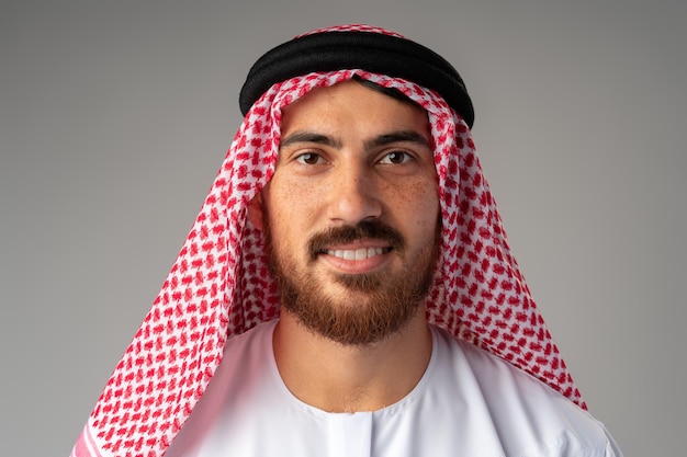Porträt eines lächelnden jungen Arabers auf grauem Hintergrund