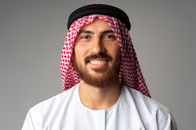 Porträt eines lächelnden jungen arabischen Mannes auf grauem Hintergrund