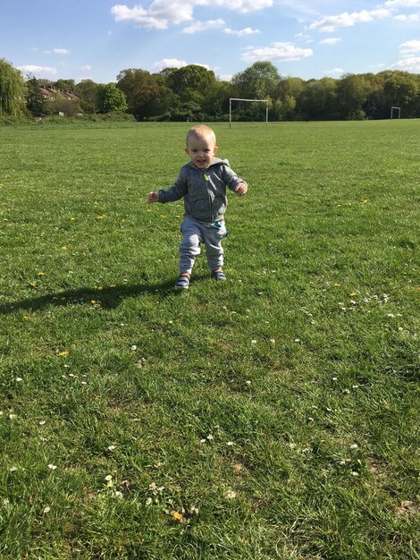 Foto porträt eines lächelnden jungen, der auf dem rasen in der stadt spazieren geht