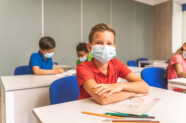 Porträt eines lächelnden Jungen, der im Klassenzimmer sitzt