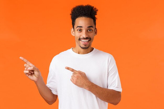 Porträt eines lächelnden jungen Mannes vor orangefarbenem Hintergrund