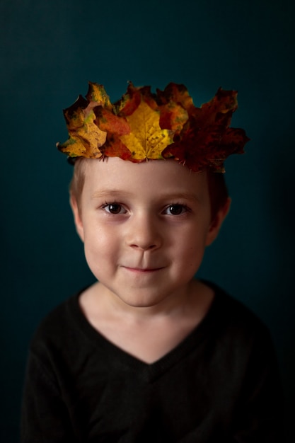 Porträt eines lächelnden Kindes mit einer Krone der Blätter auf seinem Kopf