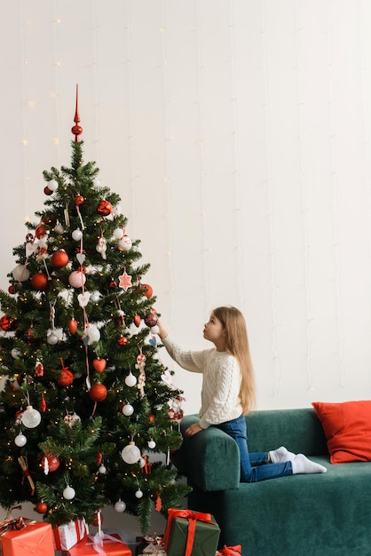 Porträt eines lächelnden kleinen Mädchens, das den Weihnachtsbaum schmückt