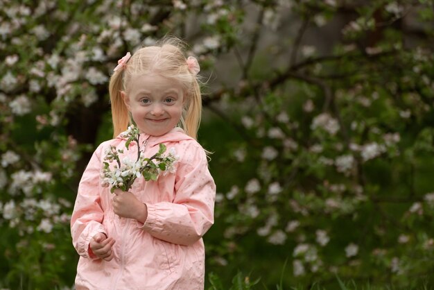Porträt eines lächelnden kleinen Mädchens in der Nähe eines blühenden Baumes Frühlingsblütenblumen für ein süßes blondes Kind im blühenden Garten
