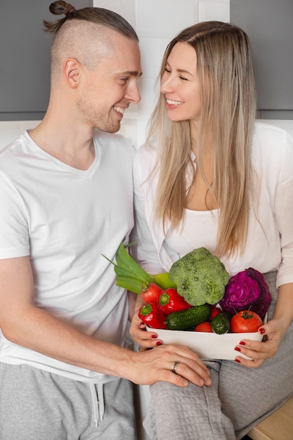 Porträt eines lächelnden Liebespaares mit einer Schüssel Gemüse