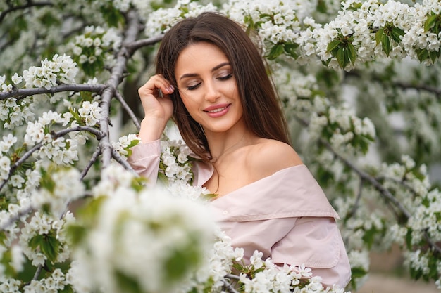 Porträt eines lächelnden Mädchens auf einem Hintergrund von weißen blühenden Bäumen