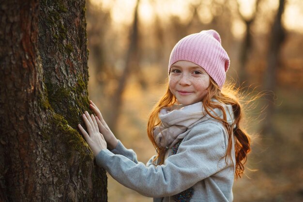 Porträt eines lächelnden Mädchens mit roten Haaren und Sommersprossen in der Nähe eines Baumes Frühlings- oder Herbstpark oder -wald