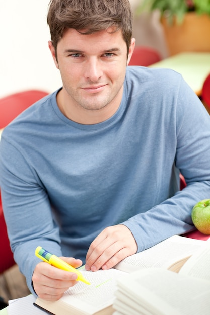 Foto porträt eines lächelnden männlichen studenten, der in der bibliothek arbeitet