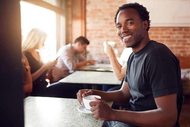 Porträt eines lächelnden Mannes, der am Tisch im Café sitzt