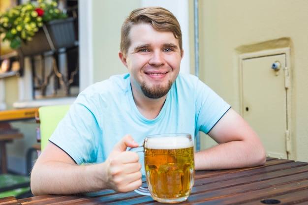 Foto porträt eines lächelnden mannes, der ein glas auf dem tisch trinkt