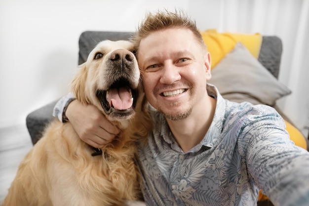 Porträt eines lächelnden Mannes, der ein Selfie mit seinem niedlichen Golden Retriever-Hund macht