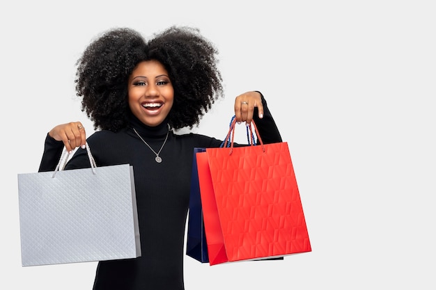 Porträt eines lächelnden schwarzen Mädchens mit Einkaufstüten isoliert auf grauem Hintergrund