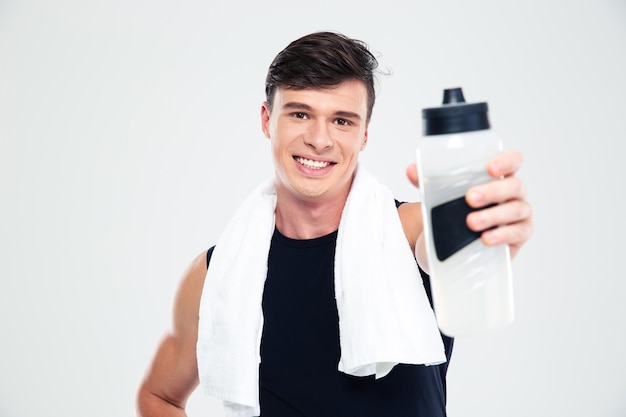 Porträt eines lächelnden Sportlers mit Handtuch, der Flasche mit Wasser an der Kamera gibt, isoliert