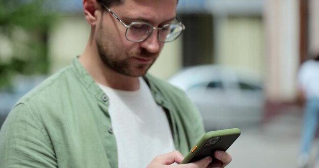 Porträt eines lässigen Mannes mit Brille mit Smartphone auf der Straße Handsom bärtiger Mann, der Nachrichten am Telefon außerhalb eingibt Online-Messaging und Surfen im Internet