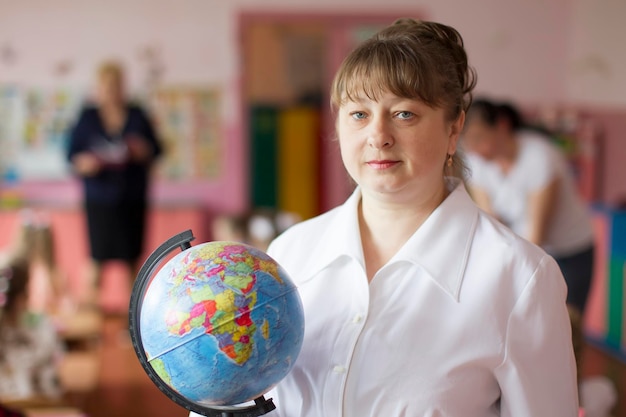 Porträt eines Lehrers mit einem Globus Ältere Lehrerin