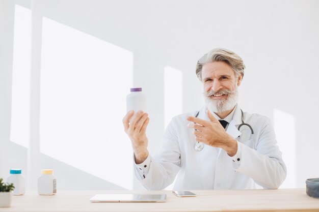 Porträt eines leitenden Arztes, der eine Flasche des Medikaments in einem Krankenhaus hält