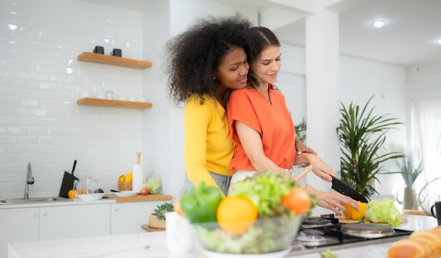 Porträt eines LGBT-Paares junger Frauen, die Salat essen und lächeln, während sie in der Küche zu Hause stehen