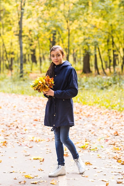 Porträt eines lustigen jungen Mädchens im Herbstwetter in der warmen Kleidung und im Hut