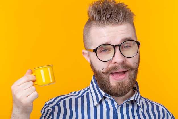 Porträt eines lustigen selbstbewussten gutaussehenden jungen Mannes in der Brille mit einem Bart mit einem kleinen Gelb