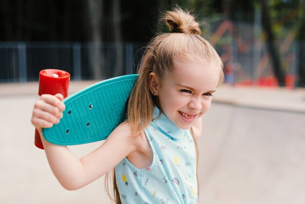 Porträt eines Mädchens, das ein Skateboard um den Hals hält und lächelt