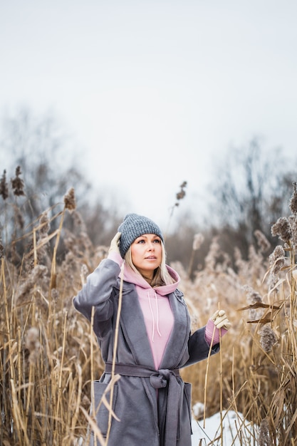 Porträt eines Mädchens des europäischen Aussehens auf einem Winterspaziergang, Gras, Wald, Feld, Hut, Gesundheit