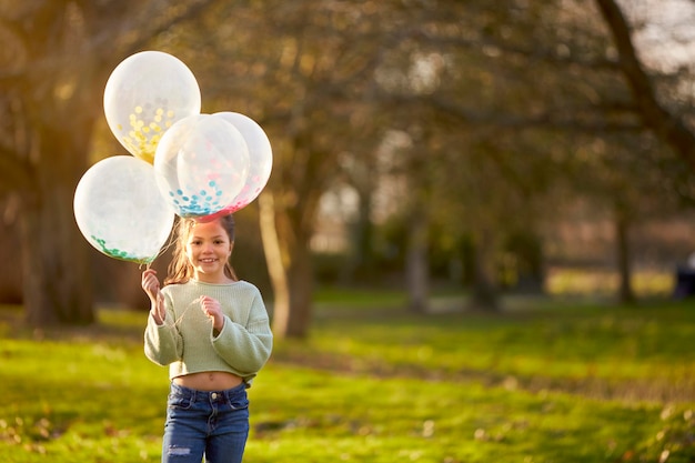 Porträt eines Mädchens im Freien auf dem Land, das mit Luftballons spielt