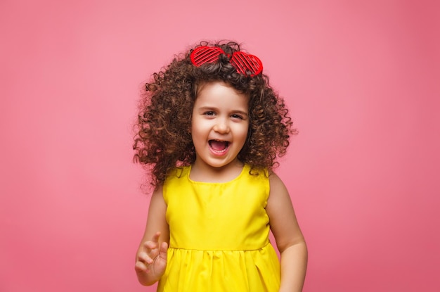 Porträt eines Mädchens in einem gelben Kleid süß attraktiv süß fröhlich fröhliches kleines Mädchen isoliert rosa Hintergrund