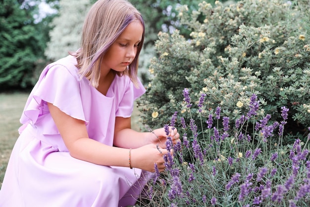 Porträt eines Mädchens in einem Kleid von einem Lavendelbusch im Garten an einem heißen Sommertag