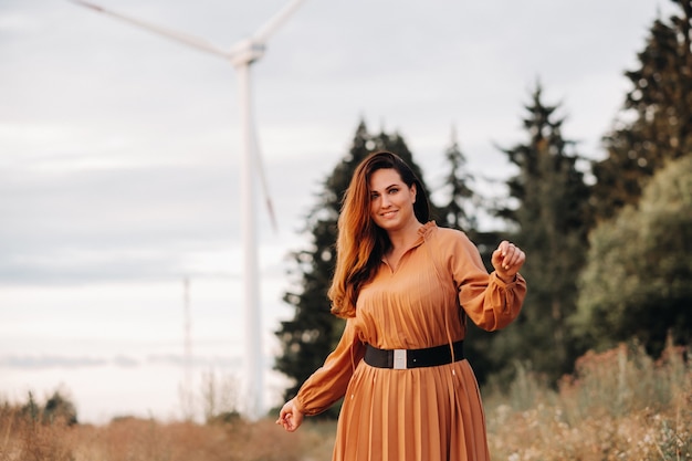 Porträt eines Mädchens in einem orange langen langen Kleid mit langen Haaren in der Natur am Abend