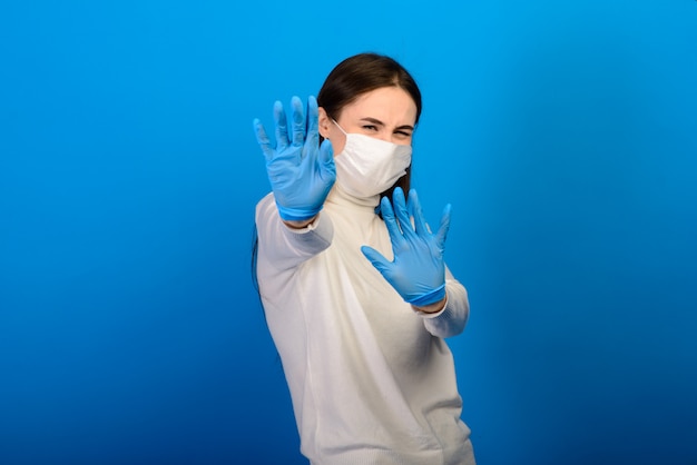 Porträt eines Mädchens in einer medizinischen Maske, die einen Gummihandschuh anzieht.