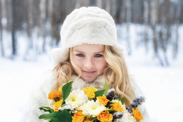 Porträt eines Mädchens mit einem Blumenstrauß im Wald im Winter
