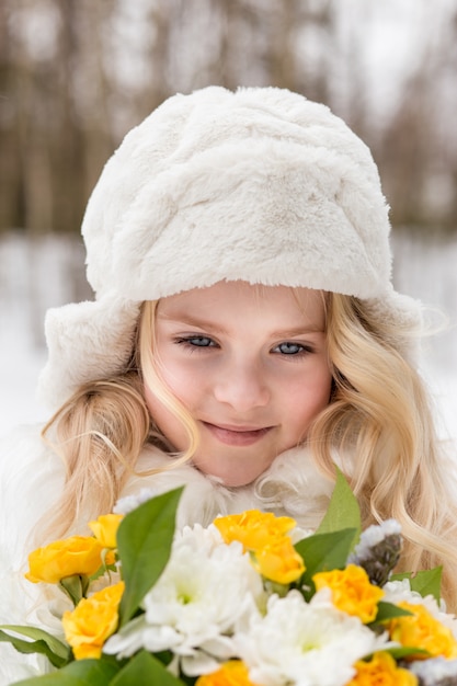 Porträt eines Mädchens mit einem Blumenstrauß im Wald im Winter