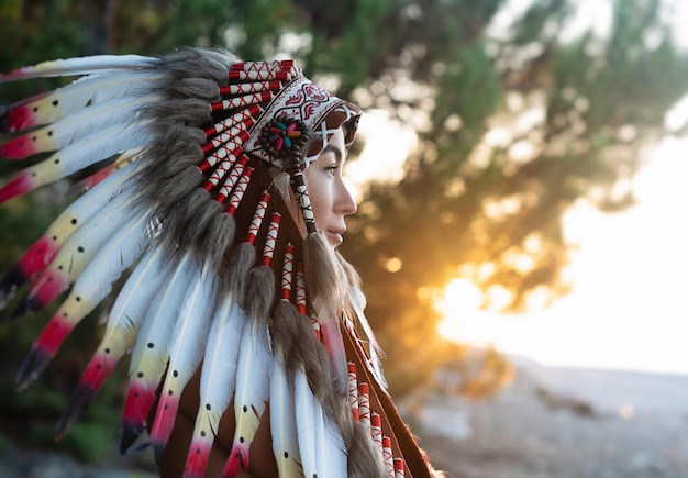 Foto porträt eines mädchens mit händen in indigenen kopfbedeckungen in der natur im sonnenuntergangslicht