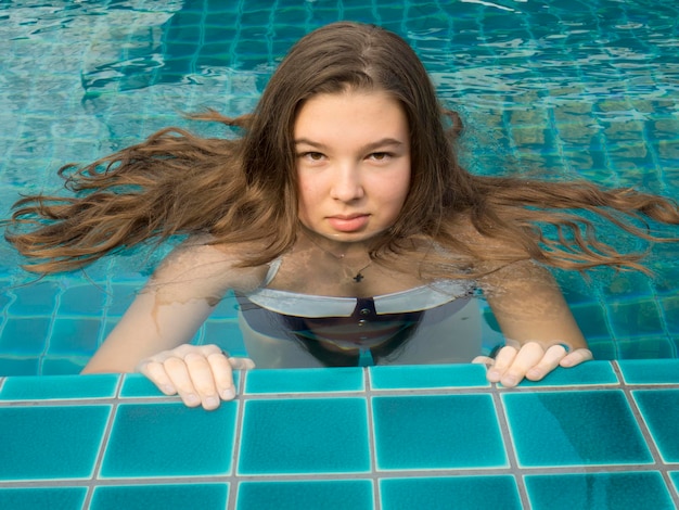 Foto porträt eines mädchens mit langen haaren, das im pool schwimmt