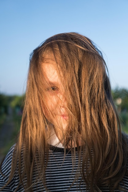 Foto porträt eines mädchens mit unordentlichen haaren gegen den blauen himmel