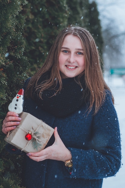 Porträt eines Mädchens mit Weihnachtsgeschenken. schneebedeckter Winterabend.