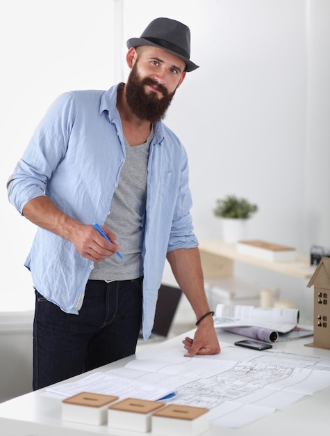 Porträt eines männlichen Designers mit Blaupausen am Schreibtisch im Büro.