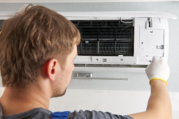 Porträt eines männlichen Technikers, der eine Klimaanlage mit einem Schraubendreher repariert