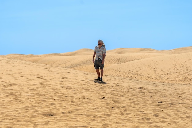 Porträt eines männlichen Touristen im Sommer, der in den Dünen von Maspalomas Gran Canaria Kanarische Inseln spazieren geht