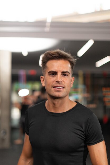 Foto porträt eines männlichen trainers, der im fitnessstudio für die kamera posiert